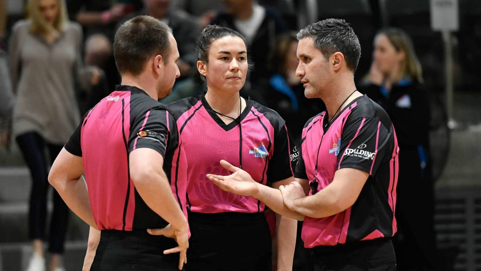 Three basketball referees conferring courtside during a game.